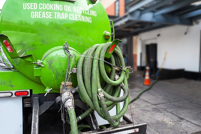 a grease trap being pumped by a sanitation technician in Amboy